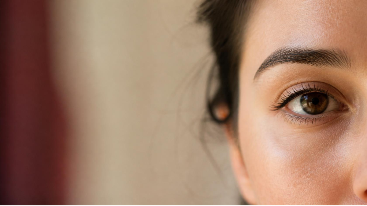 Gros plan du regard d'une femme aux cils naturels, lumière douce