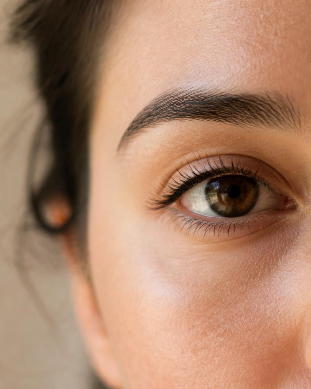 Gros plan du regard d'une femme aux cils naturels, lumière douce
